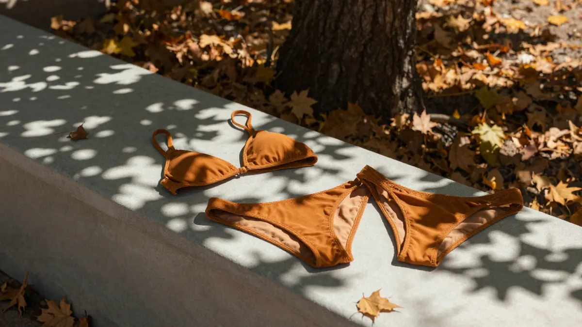 Warm amber Sugar Maple bikini on a park bench beneath a maple tree, showing its shade, fit and styling